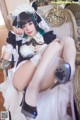 A woman in a maid outfit sitting on a chair.