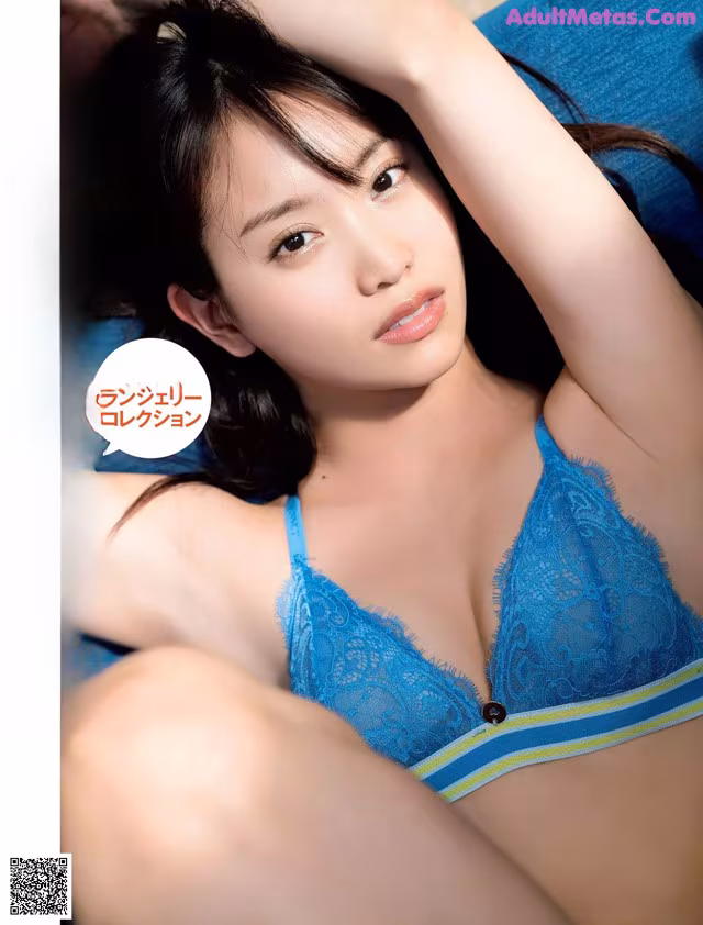 A woman in a blue bra and panties laying on a blue couch.
