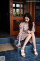 A woman sitting on the steps of a building wearing white sandals.