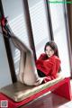 A woman in a red shirt and black pantyhose sitting on a red bench.