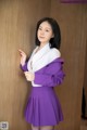 A woman in a purple skirt and white shirt posing for a picture.