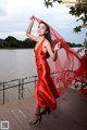 A woman in a red dress standing on a wooden dock.