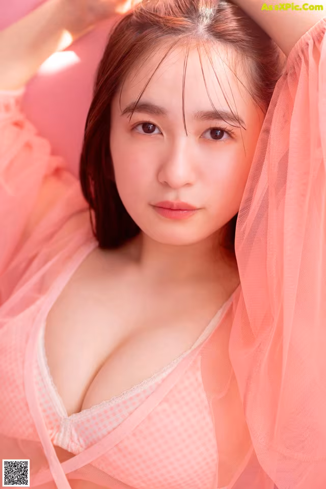 A woman in a pink lingerie laying on a pink couch.