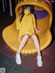 A woman wearing a yellow dress sitting on a yellow slide.