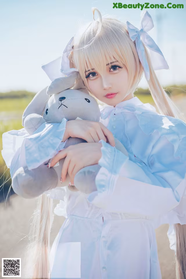 A woman in a white dress holding a stuffed animal.