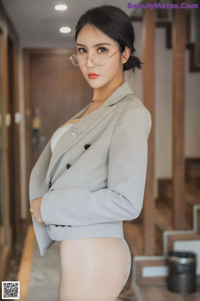 a woman in a gray suit and glasses posing for the camera