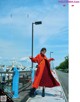 A woman in a red coat is walking on a bridge.