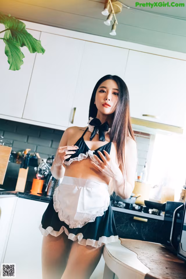A woman in a black and white dress standing in a kitchen.