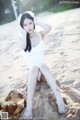 A woman in a white bathing suit sitting on a beach.