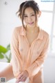 A woman in an orange shirt sitting on a white chair.